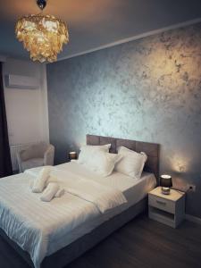 1 dormitorio con 1 cama blanca grande con lámpara de araña en The Chalet, en Mamaia Nord – Năvodari