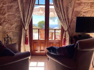 a living room with a television and a window at Boutique apart-hotel Galini, member of the best small hotels in Greece, Adults only in Volímai
