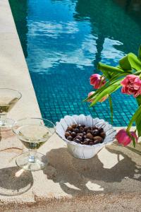 eine Schale mit Weintrauben und Weingläsern neben einem Pool in der Unterkunft Vila Branca Guesthouse - Palacete in Figueira da Foz