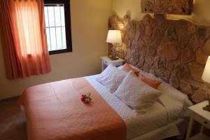 a bedroom with a large bed with a stone wall at Cortijo de las cañadas in Venta de Mendoza