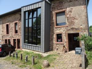 ein Steinhaus mit schwarzen Fenstern und einem Auto, das draußen parkt in der Unterkunft BOIS DE CHENES HOUSE in Phalsbourg