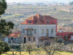 uma casa velha com um telhado vermelho numa colina em Solar dos Alperces - Serra da Estrela - Turismo de Aldeia em Travancinha