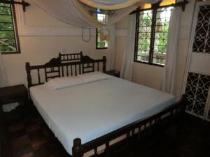 Un dormitorio con una cama grande en una habitación con ventanas. en Villa Lamuhouse Diani Beach, en Diani Beach 20 fotos más