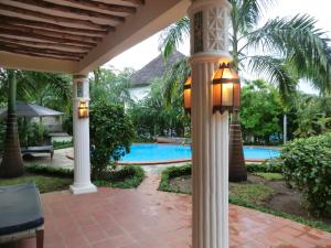 une terrasse couverte avec colonnes et une piscine dans l'établissement Villa Lamuhouse Diani Beach, à Diani Beach