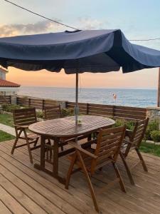 a wooden table and chairs with an umbrella on a deck at Christina Apartment in Ágios Konstantínos +7 photos