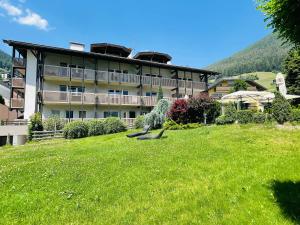 a large building with a green lawn in front of it at Residence Hotel Alpinum in Campo Tures