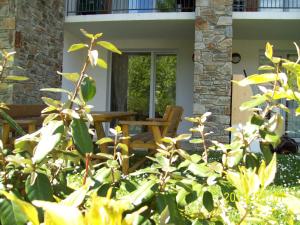 a porch with a wooden bench and a table at Hébergement Coup de Coeur in Ax-les-Thermes