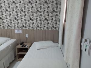 a small room with two beds and a wall at Hotel Mandino in Alta Floresta