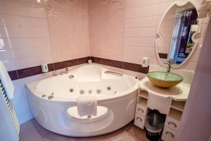 ein Badezimmer mit einer Badewanne, einem Waschbecken und einem Spiegel in der Unterkunft Hotel Erzsébet in Hévíz