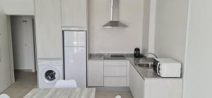 una cocina blanca con lavadora y secadora. en Apartamentos Tarifa Sun, en Tarifa