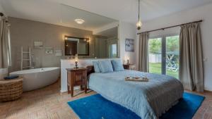a bedroom with a large bed and a bath tub at Luxury Villa With Pool in Vineyard Near the Beach in Porches +21 photos