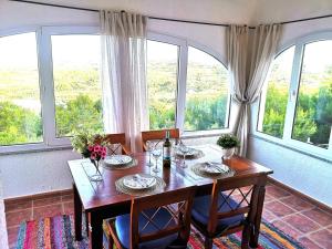 comedor con mesa de madera y ventanas grandes en Casa Karma - Villa with private pool and views, en Benitachell
