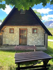 un banc en bois devant une maison en pierre dans l'établissement Apartman A&A, à Žabljak