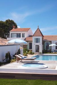 - une piscine avec un banc et un parasol à côté d'une maison dans l'établissement Les Hautes Mers, à L'Ile d'Yeu