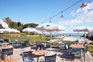 a patio with tables and umbrellas and a pool at Les Hautes Mers in L'Ile d'Yeu