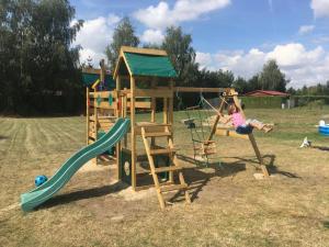 a young girl is playing on a playground at Domek nad jeziorem in Izdebno