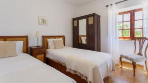 a bedroom with two beds and a chair and a window at Cozy Algarve Home with Vineyard View Near Beaches in Porches