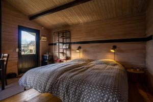 a bedroom with a bed in a room with wooden walls at Hedelandets Camping in Sevel