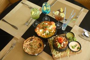 a table topped with plates of food and drinks at RIVERSIDE MEADOWS in Vidisha +10 photos