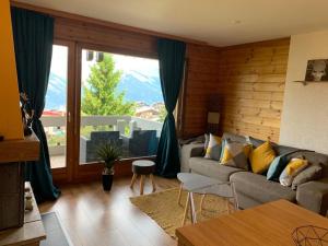 a living room with a couch and a large window at Studio Hauts-de-Nendaz G2 ski in-out in Nendaz