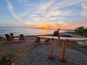 a surfboard on a stand on a beach with a sunset at Apartments Lolo in Privlaka