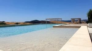 una piscina de agua azul y dos bancos en Agriturismo L'impero, en Santa Luce