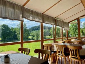 BlaibachにあるGasthof Pension Fischerstüberlのテーブルと椅子、大きな窓のあるレストラン