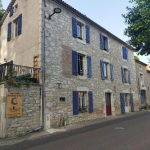 un edificio de piedra con persianas azules en una calle en Un nid pour la nuit, Chambres d’hôtes, en Saint-Géry