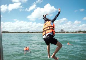 沙美島的住宿－沙美島君怡度假酒店，背上一只狗跳入水中的人