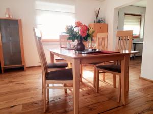 a dining room table with chairs and a vase with flowers at Appartement - FeWo Wenne in Langenau