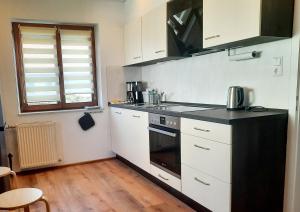 una cucina con armadi bianchi e un forno a piano cottura nero di Appartement - FeWo Wenne a Langenau