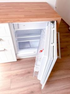 an empty refrigerator with its door open in a kitchen at Upės apartamentai in Birštonas