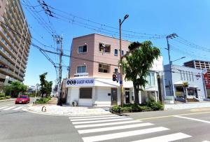 a building on the corner of a street with a crosswalk at ABC Guesthouse (1F) in Izumi-Sano