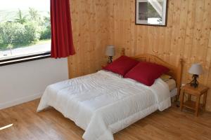 um quarto com uma cama com almofadas vermelhas e uma janela em Grand studio 6 pers. Super Besse, Résidence *** em Besse-et-Saint-Anastaise