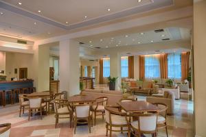 a restaurant with tables and chairs in a lobby at Corfu Hellinis Hotel in Corfu