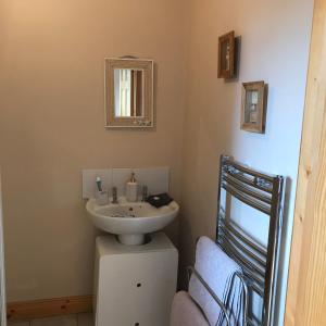 uma casa de banho com um lavatório, um espelho e uma cadeira em The perfect rest place em Omagh