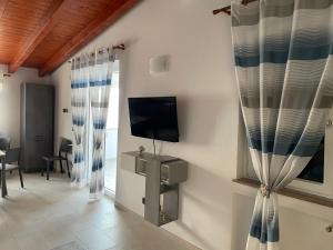 a living room with a tv and curtains at Casa vacanze “ il Tramonto” in Milazzo