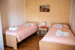 two beds in a small room with pink sheets at Casa Roberto - piano terra con giardino in Levico Terme