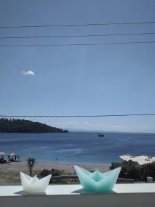 two white paper boats sitting on a window with a beach at Anastasia Studios & Apartments in Panormos Skopelos