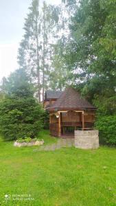 a wooden pavilion in a grassy yard with a building at Садиба У Надії in Guta