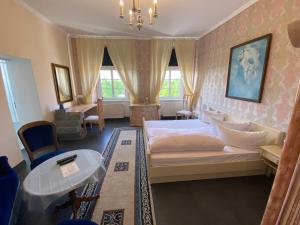 Schlafzimmer mit einem Bett, einem Tisch und Fenstern in der Unterkunft Jagdschloss lalendorf in Lalendorf