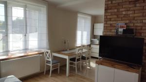 a kitchen with a table with chairs and a tv at Apartament Słoneczny Węgorzewo 74m2 in Węgorzewo