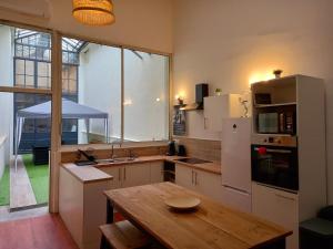 a kitchen with a wooden table and a large window at T5 L'ATELIER in Valence-dʼAgen