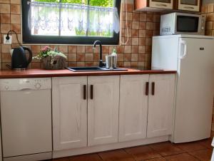 uma cozinha com armários brancos e um frigorífico branco em Domki Klara em Pobierowo