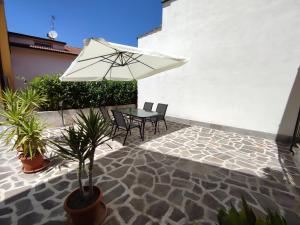een patio met een tafel en stoelen en een parasol bij Casa Laura in Corfinio