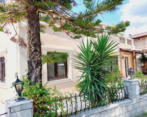 a house with a tree in front of a fence at ZOI & ALEXIA APARTMENTS in Ipsos