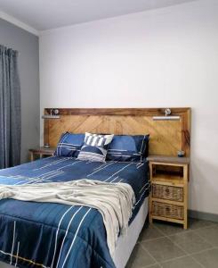 1 dormitorio con cama azul y cabecero de madera en Greystoke - Furnished, self service apartment. en Springs