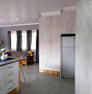 a kitchen with white cabinets and a refrigerator at Greystoke - Furnished, self service apartment. in Springs