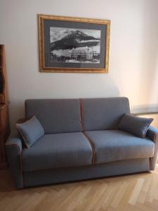a blue couch in a living room with a picture on the wall at La Stella Alpina in Colle Isarco