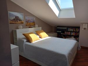 Un dormitorio con una cama con almohadas amarillas y una ventana en La mansarda di Mi&Lo junior suite en Bollate